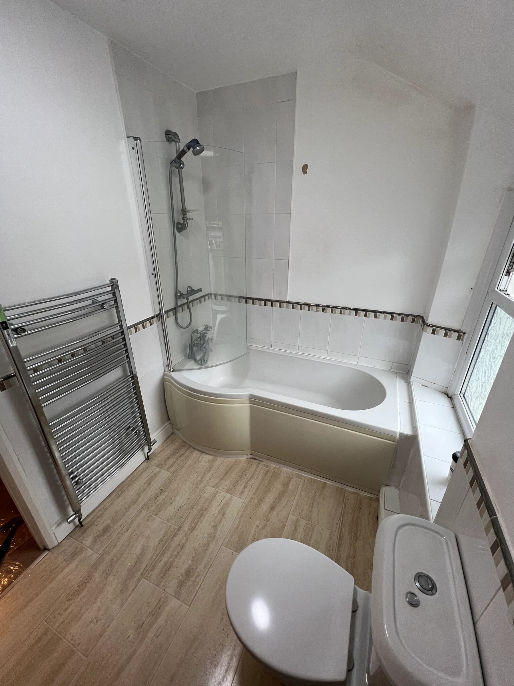 An existing corner bath and shower screen in a Caerphilly bathroom before Truscon replaced it