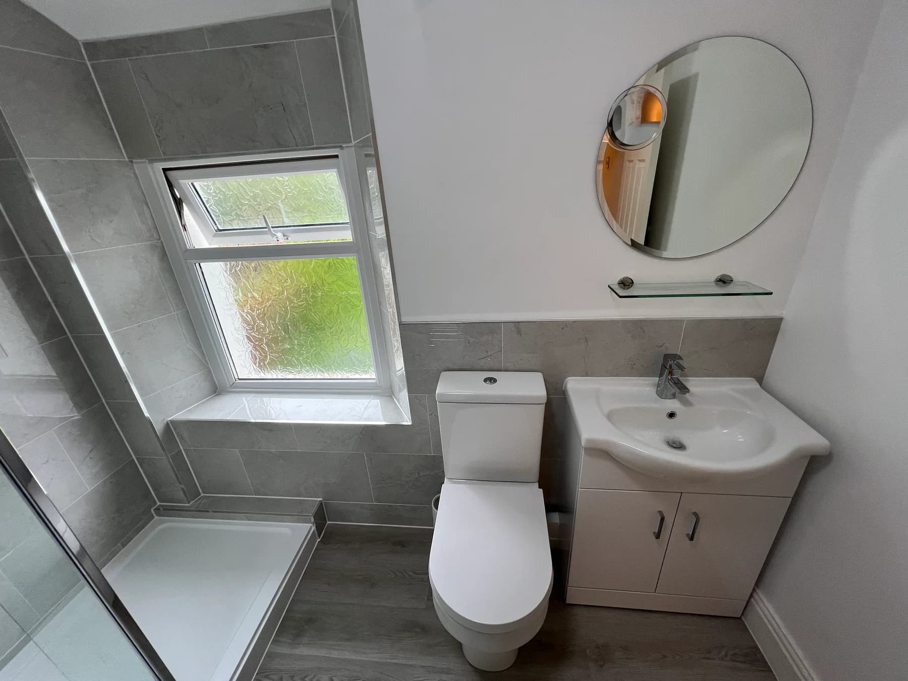 A completed Truscon bathroom installation in Caerphilly with grey wall tiles, a shower tray and a fitted vanity unit