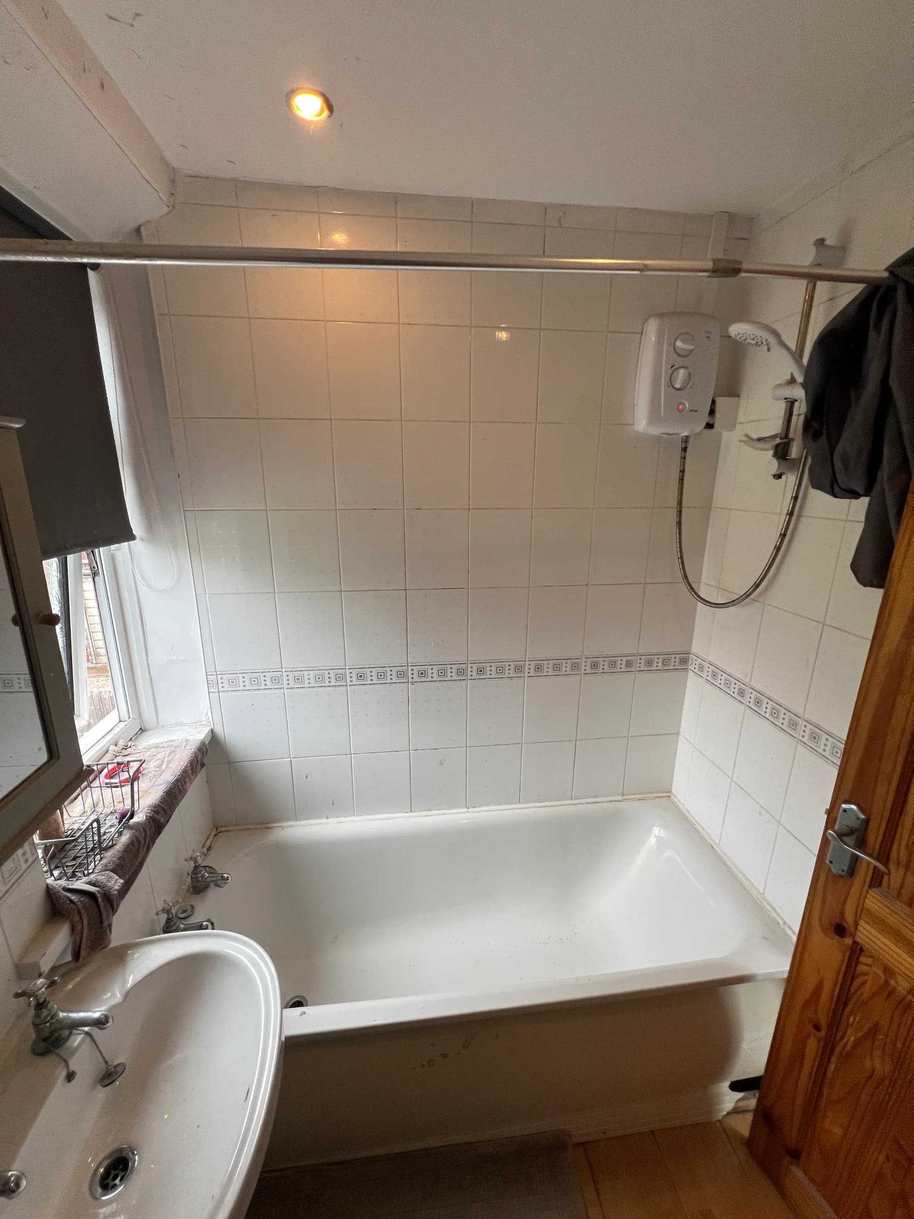 A dated tiled bathroom in Caerphilly with an electric shower over the bath, photographed before Truscon renovated it