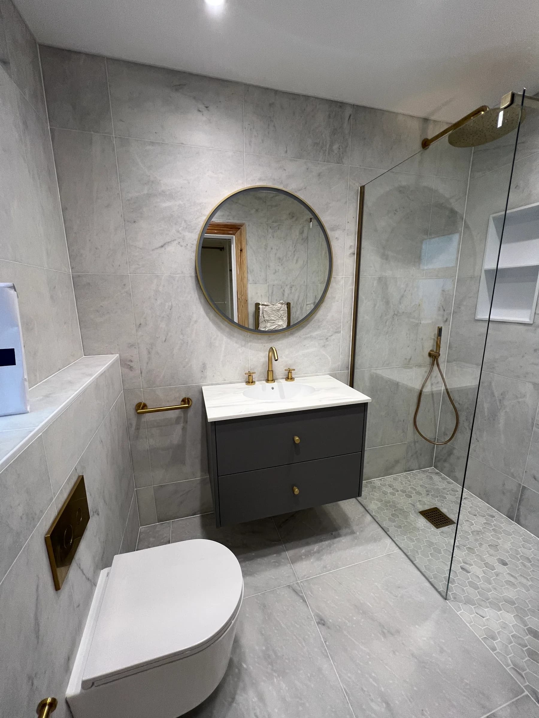A finished Truscon bathroom in Caerphilly with marble-effect tiling, a wall-hung vanity unit and a walk-in shower