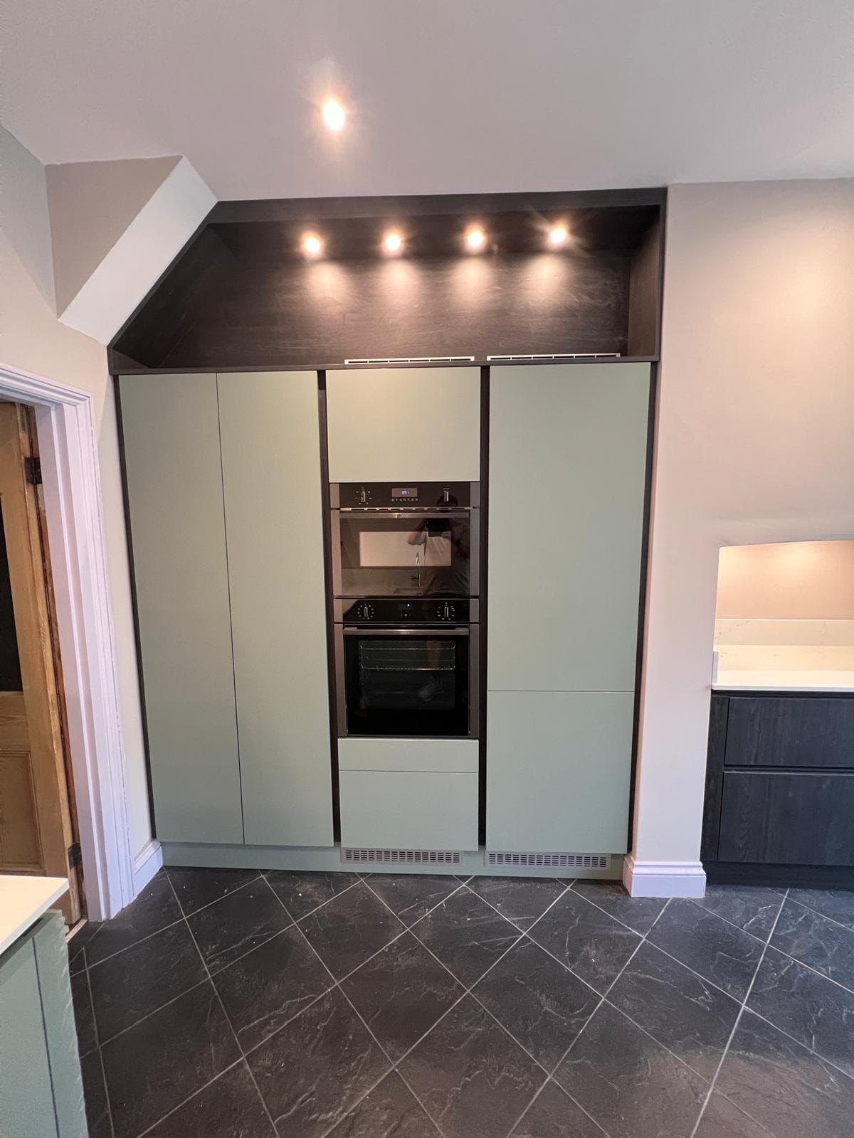 Tall sage green units with built-in double oven and downlights, fitted by Truscon