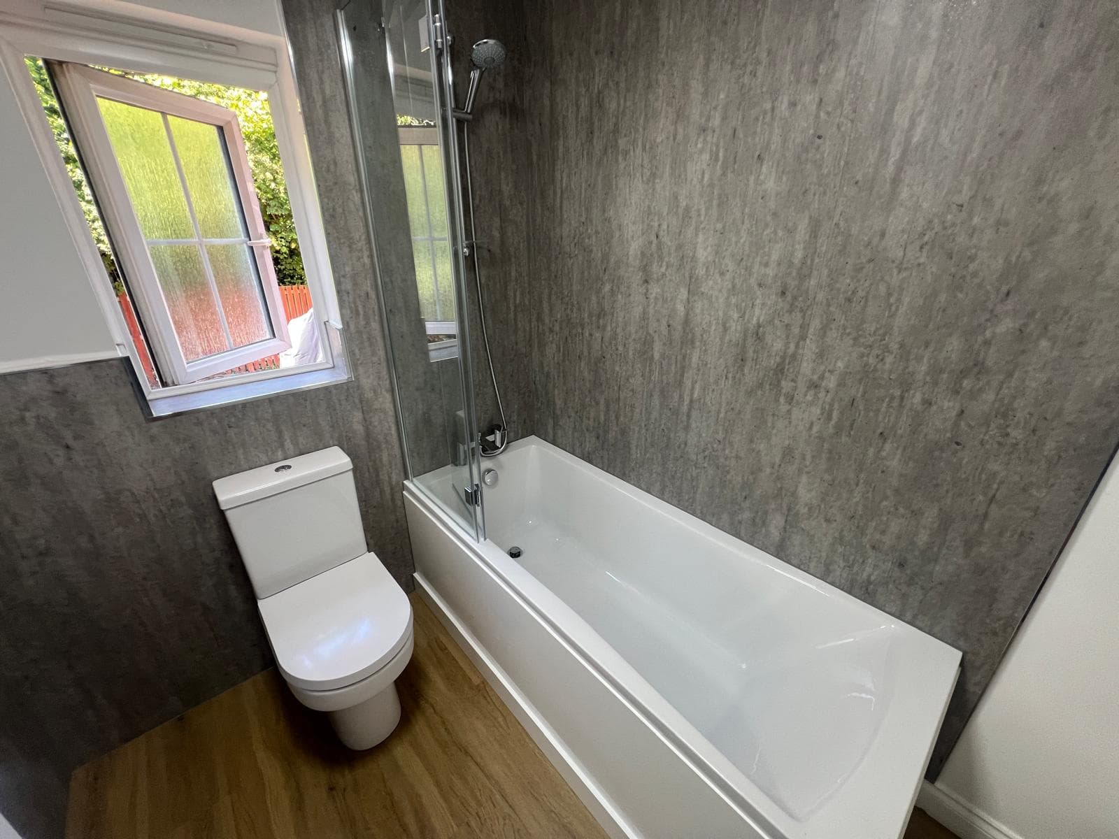 Bathroom with stone-effect wall panels, bath and shower screen, fitted by Truscon